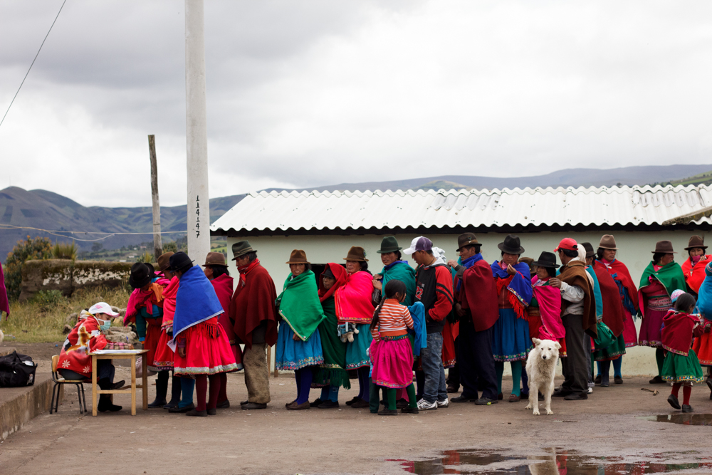 Community members in traditional Andean clothing line up at a MEDLIFE mobile clinic registration table near Riobamba, Ecuador